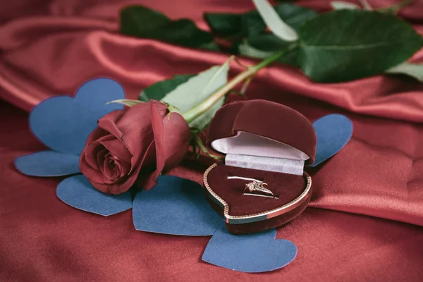 Diamantring und Rose auf leuchtend rotem Hintergrund — Stockfoto