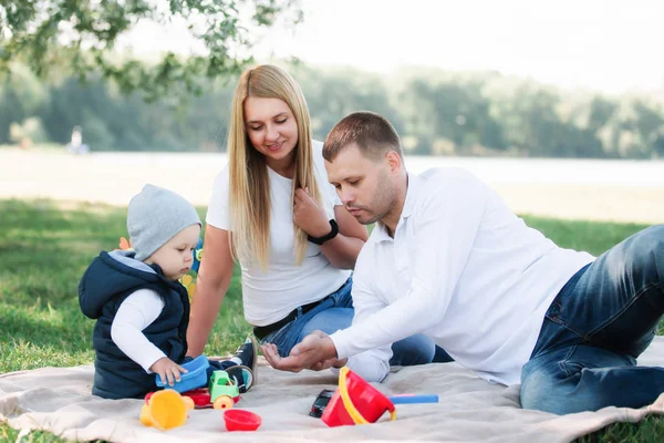 Little boy playing toy cars and having fun with his father and mother outdoors — Stock Photo, Image