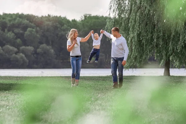 Щасливі батьки зі своїм маленьким сином ходять разом у весняному парку — стокове фото