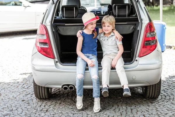 여동생과 오 빠의 가방을 차 트렁크에 앉아 — 스톡 사진