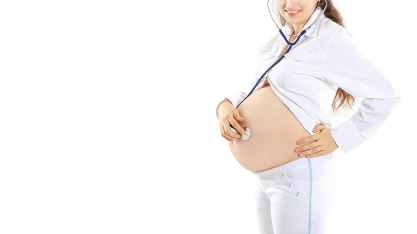 Femme enceinte écoutant son bébé avec un stéthoscope  , — Photo