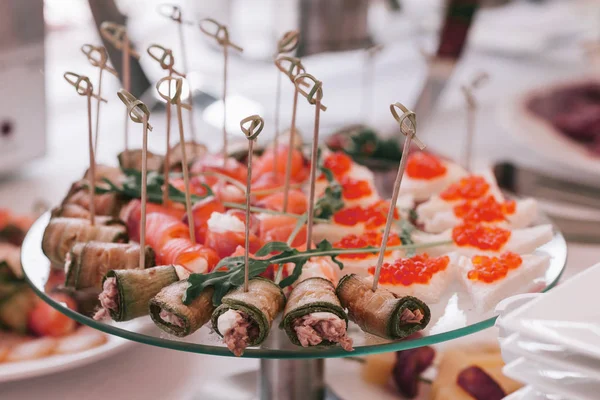 Salmon rolls, sandwiches with red caviar and other snacks on the festive table — Stock Photo, Image