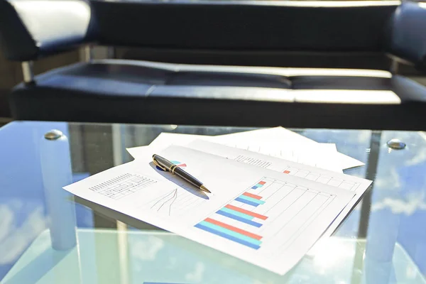 Financial chart and pen on glass table in office — Stock Photo, Image