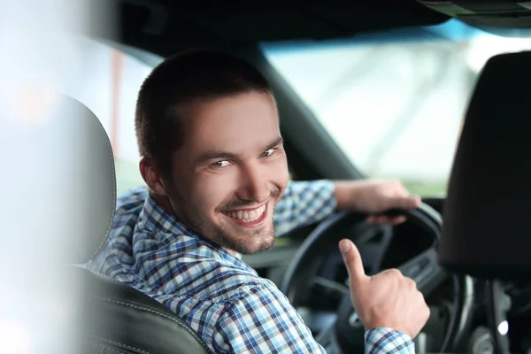 Współczesny człowiek siedzi w samochodzie i wyświetlane jego kciuk. — Zdjęcie stockowe