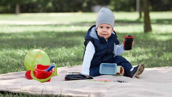 Menino bonito brincando com um carro de brinquedo sentado no gramado — Fotografia de Stock