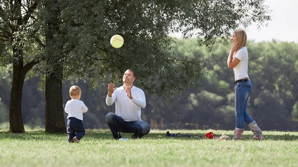 Familia feliz con su hijo pequeño en un paseo por el parque de la ciudad . —  Fotos de Stock