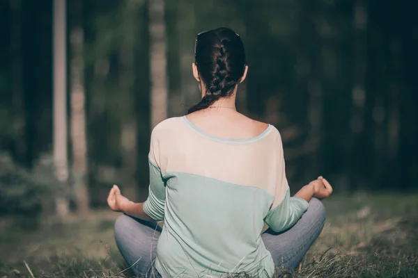 Vue arrière. jeune femme assise en position Lotus à l'extérieur — Photo