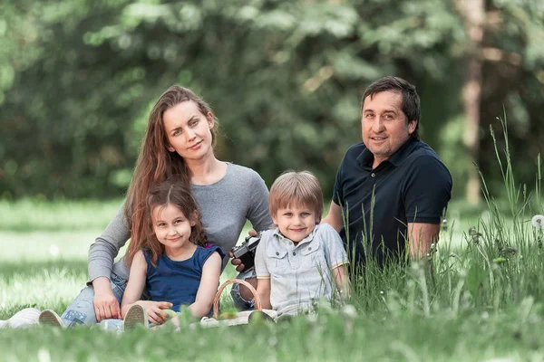 Родители с маленькими двумя детьми на газоне в весенний день — стоковое фото
