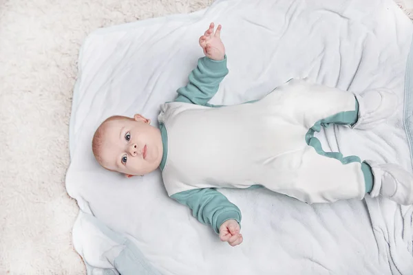 Schattig kind in een pinguïn pak liggend op een deken. — Stockfoto