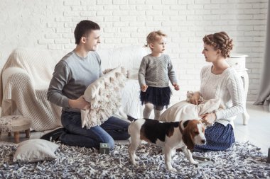 mutlu aile geniş oturma odasında bir evcil köpek ile oynarken