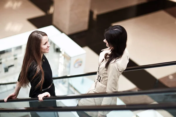 Zwei lächelnde Geschäftsfrauen auf einer Rolltreppe in einem Business Center — Stockfoto