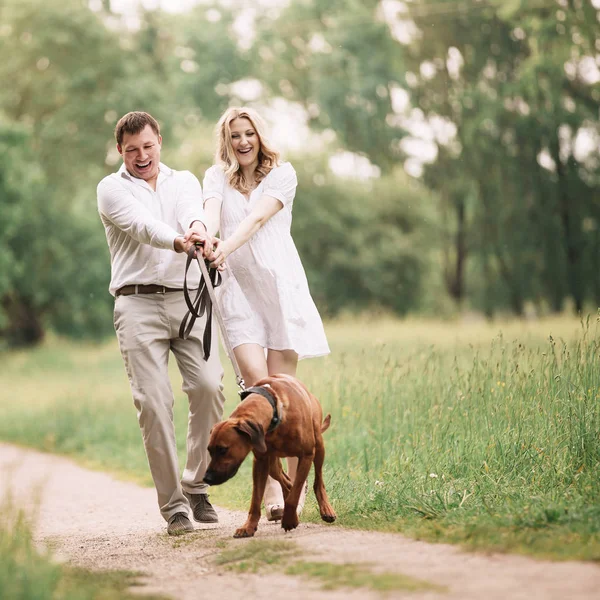 Junger Mann und seine Frau haben Spaß mit ihrem Haustier Hund — Stockfoto