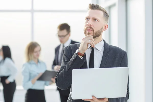 Empresario pensativo con portátil de pie en el pasillo de la oficina . — Foto de Stock