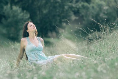 düşünceli genç kadın yaz gökyüzüne bakıyor .