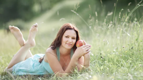 Young beautiful woman with Apple resting on fresh green grass — Stock Photo, Image