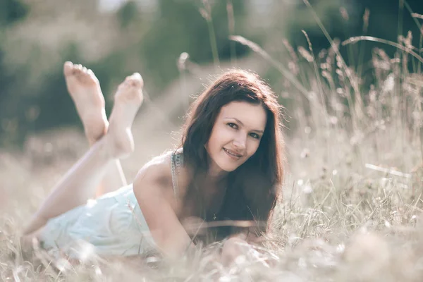 Brooding young woman lying on grass on summer day. — Stock Photo, Image