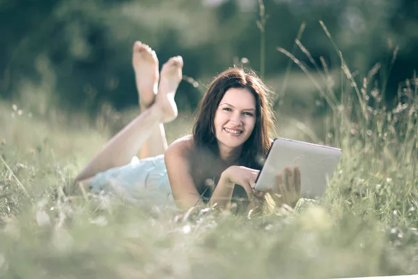 Uśmiechnięta młoda kobieta z cyfrowym tablecie na lato łąka tła. — Zdjęcie stockowe
