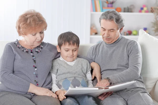 Любящие бабушка и дедушка с внуком, сидящими на диване — стоковое фото