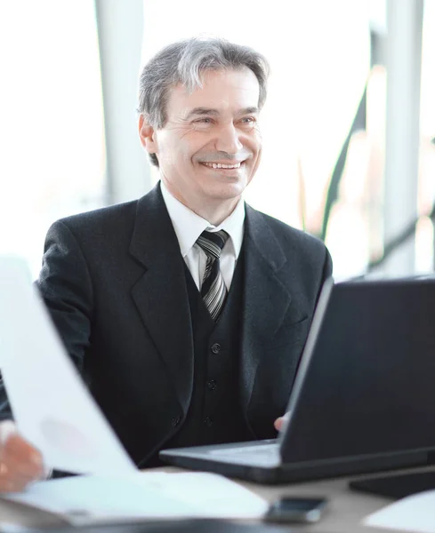 Uśmiechający się biznesmen senior siedzący przy biurku — Zdjęcie stockowe