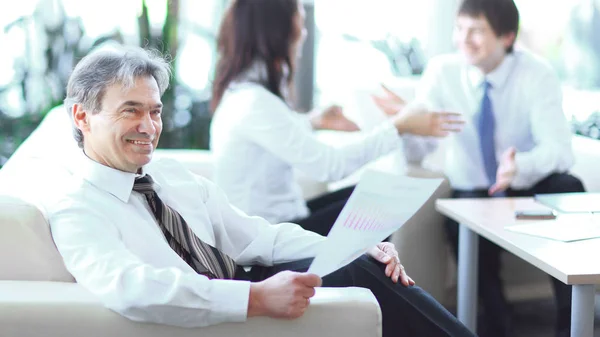 Hombre de negocios ponderando un documento sentado en una oficina moderna — Foto de Stock