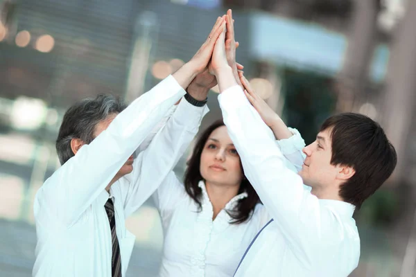 Leden van het team van de zakelijke geven elkaar een high-vijf, permanent in het kantoor — Stockfoto
