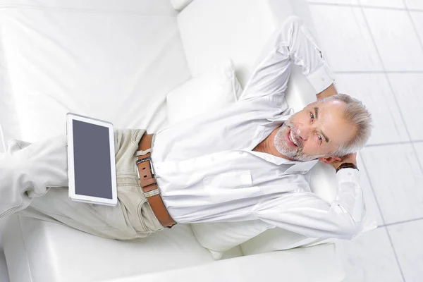 Senior businessman looking at digital tablet screen sitting on sofa — Stock Photo, Image