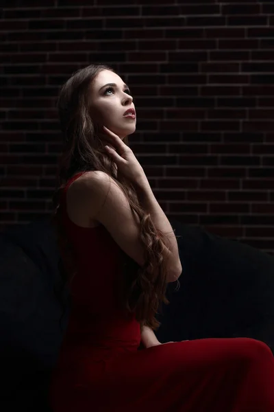 椅子に座って赤いドレスのスタイリッシュな若い女性 — ストック写真