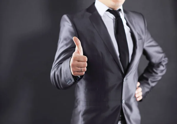 Close up. Young businessman showing thumbs up.isolated on black — стоковое фото