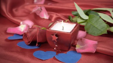kırmızı ipek arka planda mum ve gül