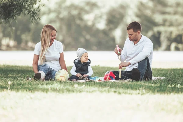 Parents and their little son blowing bubbles on a summer day walk. — Stock Photo, Image