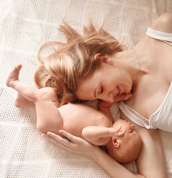 happy mom with newborn daughter lying on the bed