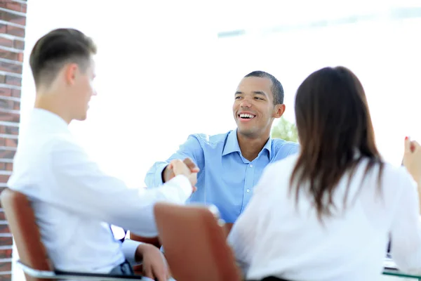 Gente de negocios apretón de manos sentado en un escritorio — Foto de Stock