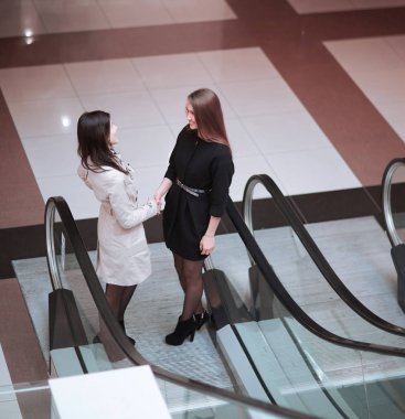 söz, iş merkezinde yürüyen merdiven üzerinde duran iki iş kadınları