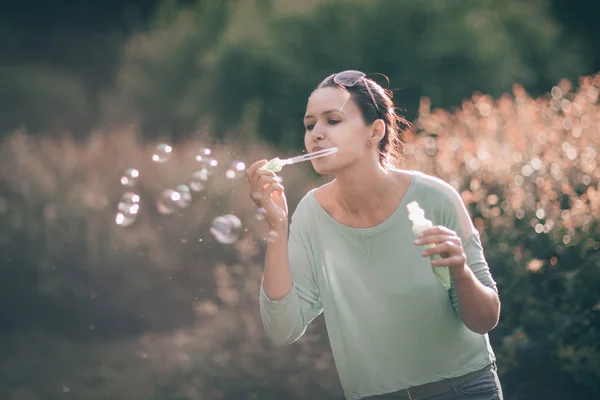 Beautiful young woman blowing soap bubbles in the Park Sunny — Stock Photo, Image