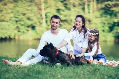 Güneşli bir yaz gününde piknikte köpekli mutlu bir aile. pregn