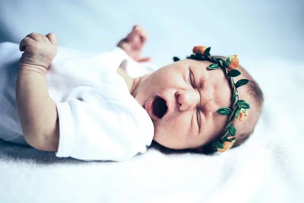 Serene nyfödda baby på en säng gäspningar — Stockfoto