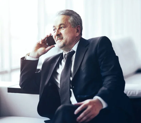 Podnikatel v kanceláři sedí na pohovce mluví o telefonu — Stock fotografie
