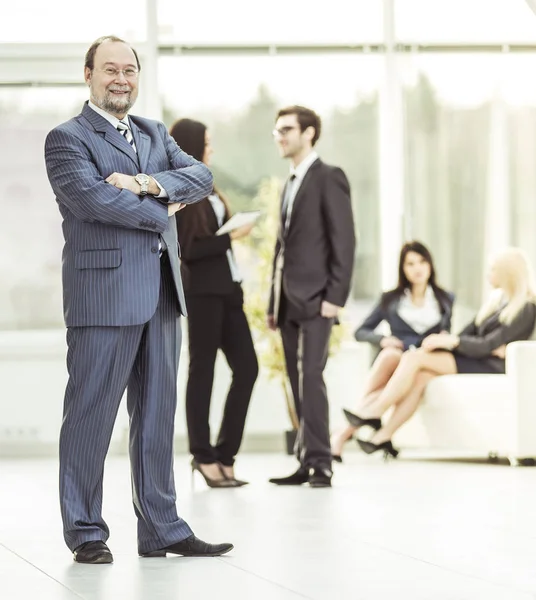 Photo in full growth - a successful businessman on the background of business team in the spacious office — Stock Photo, Image