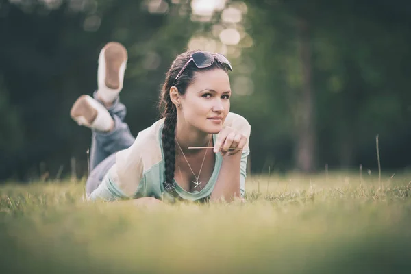 Pensive young woman lying on the grass on a good day — Stock Photo, Image