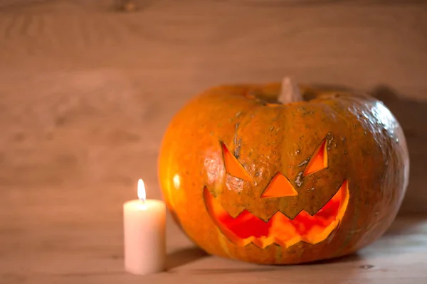 Ljus och en läskig leende Halloween pumpa på ett träbord — Stockfoto