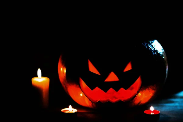 Candle and a creepy smiling Halloween pumpkin on a wooden table — Stock Photo, Image