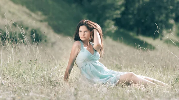 Mujer joven y melancólica sentada en la hierba de un prado de verano. — Foto de Stock