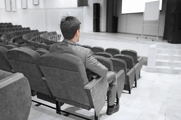 Obchodník sedící v prázdné konferenční síni — Stock fotografie