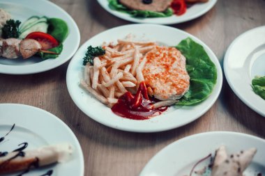 yemek masasında bir tabakta domuz pirzolası ve kızarmış patates