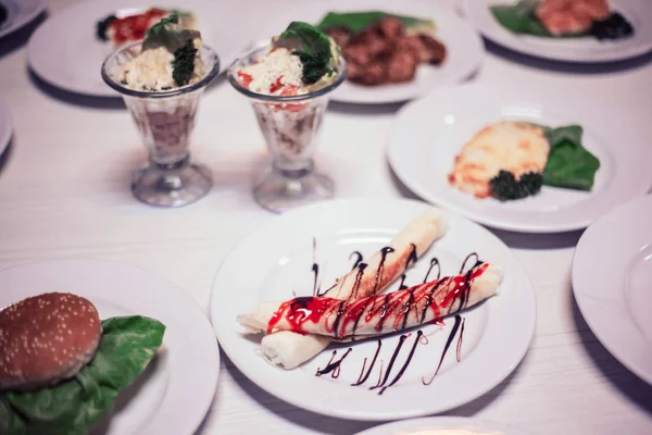 Vékony blinchiki édes mártással, hamburger és egyéb ételek az asztalra a kávézóban — Stock Fotó