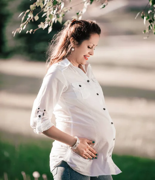 Счастливая беременная женщина смотрит на свой живот — стоковое фото