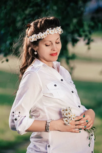 ヒナギクの花束を持つかわいい妊娠中の女性の肖像画 — ストック写真