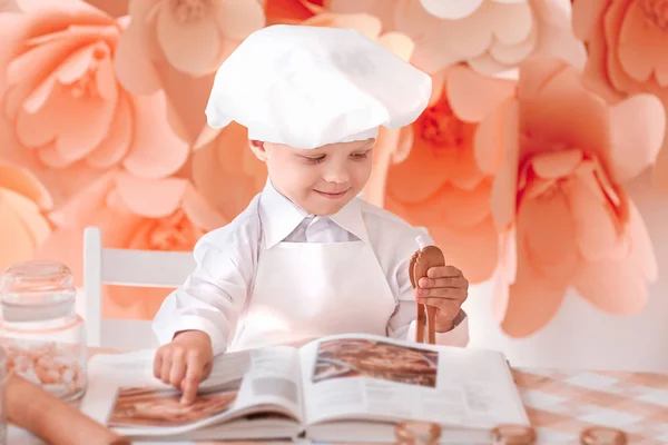 Счастливый мальчик шеф-повар выбирает кулинарный рецепт — стоковое фото