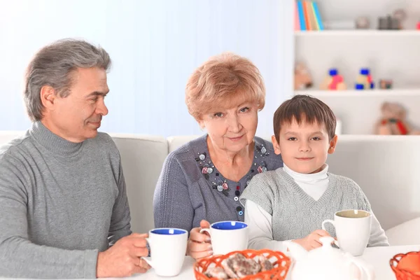 Chico bebiendo chocolate caliente y abuelos felices —  Fotos de Stock