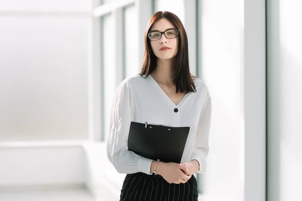 Молодая деловая женщина, стоящая в светлом офисе — стоковое фото